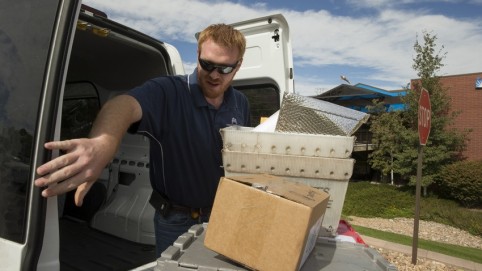 Courier taking packages out of the back of his van 